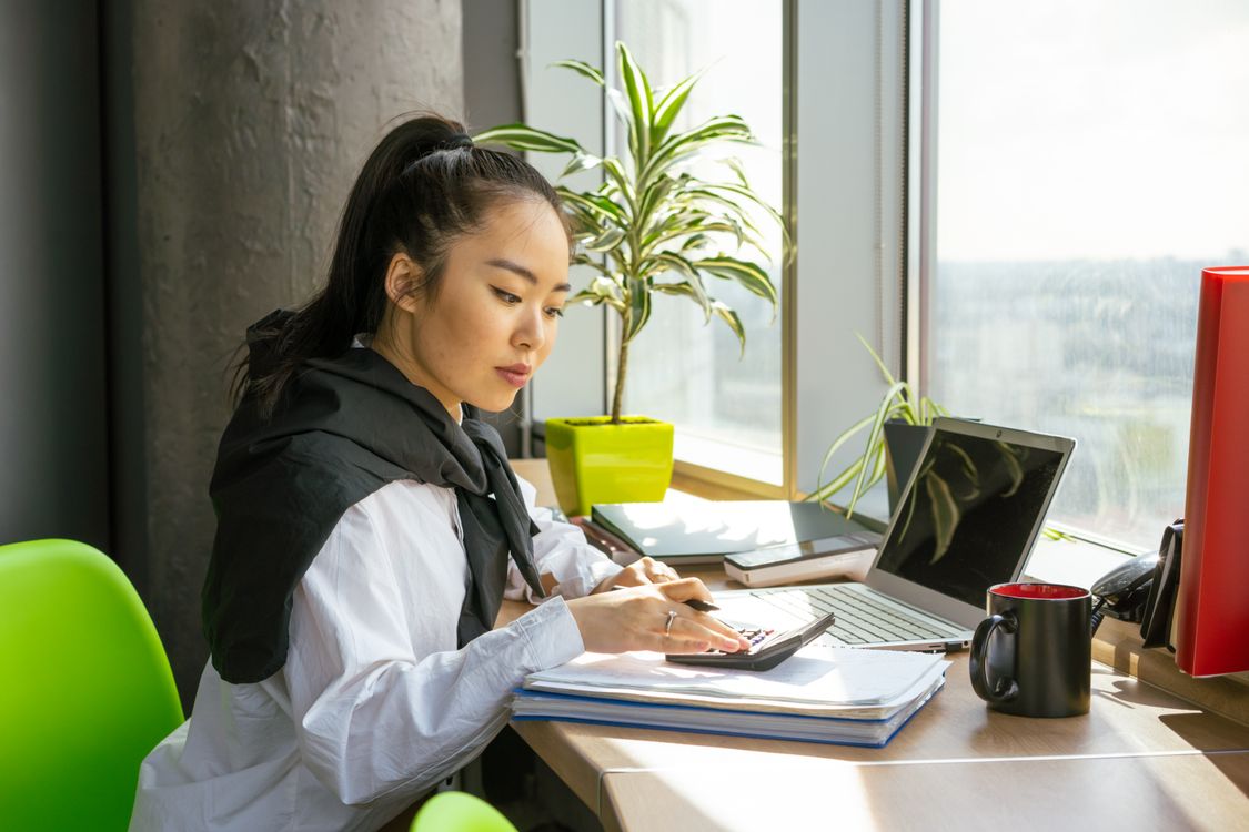 A woman working with paperwork and a calculator at her desk